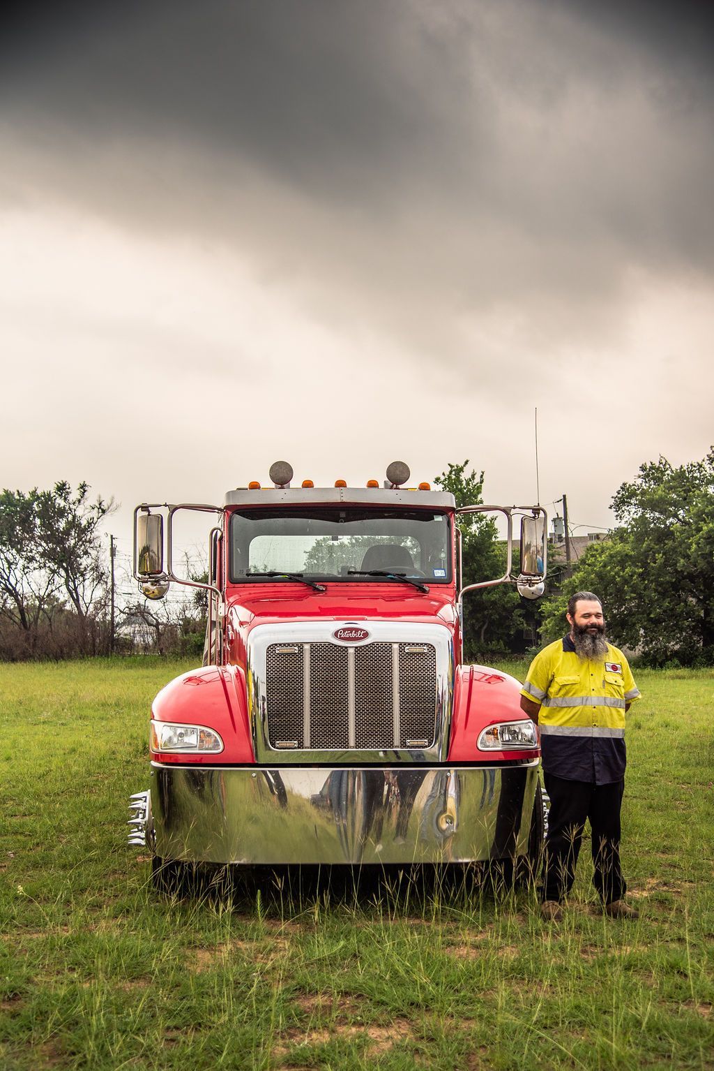 A man is standing in front of a red semi truck in a field. | Chuck's Garage