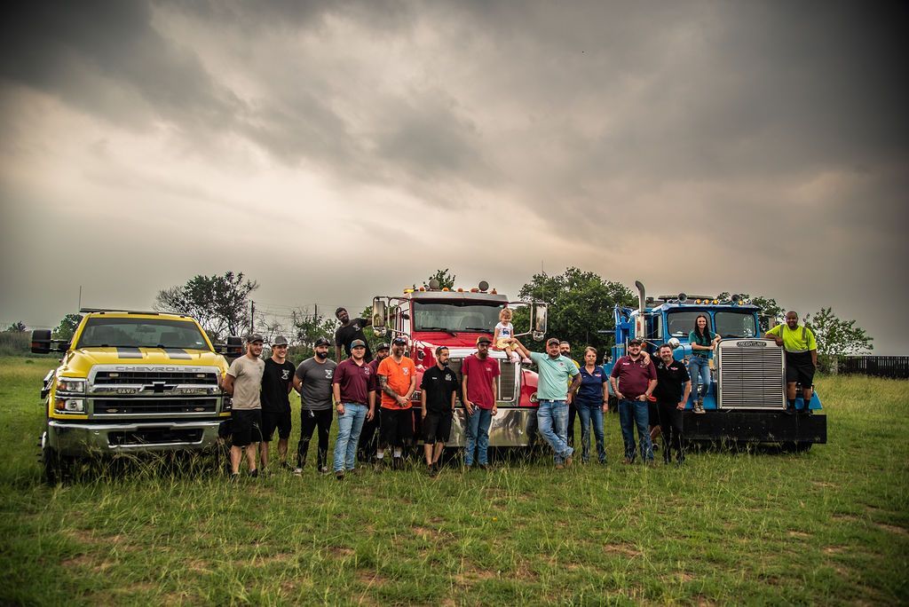 A group of people standing in front of trucks in a field. | Chuck's Garage