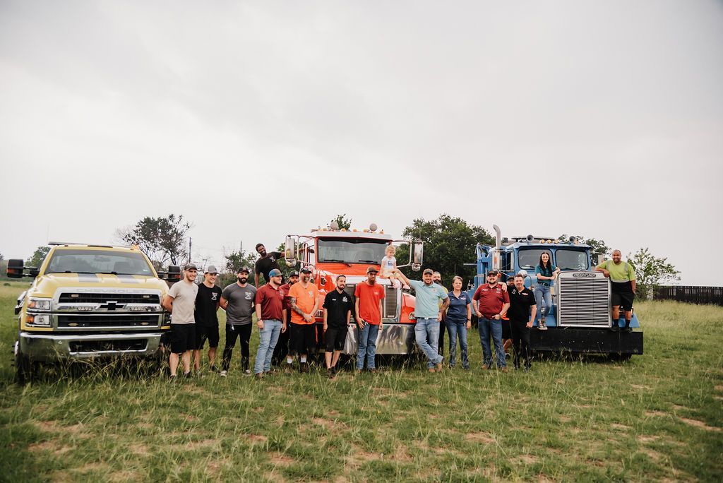 A group of people standing next to trucks in a field. | Chuck's Garage
