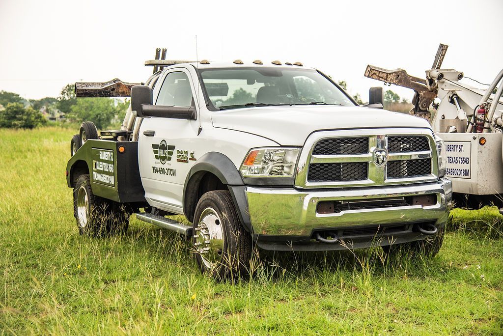 A white tow truck is parked in a grassy field. | Chuck's Garage