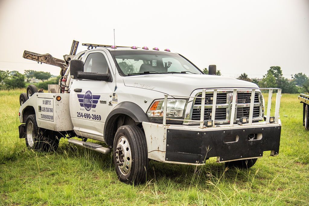 A white tow truck is parked in a grassy field. | Chuck's Garage