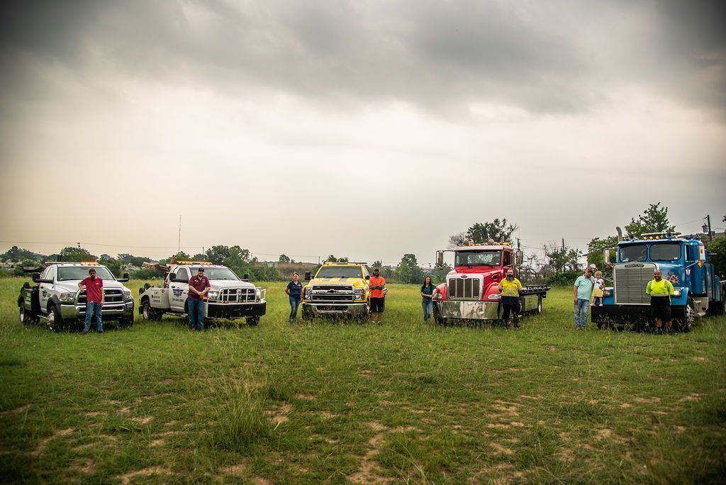 A group of tow trucks are parked in a grassy field. | Chuck's Garage