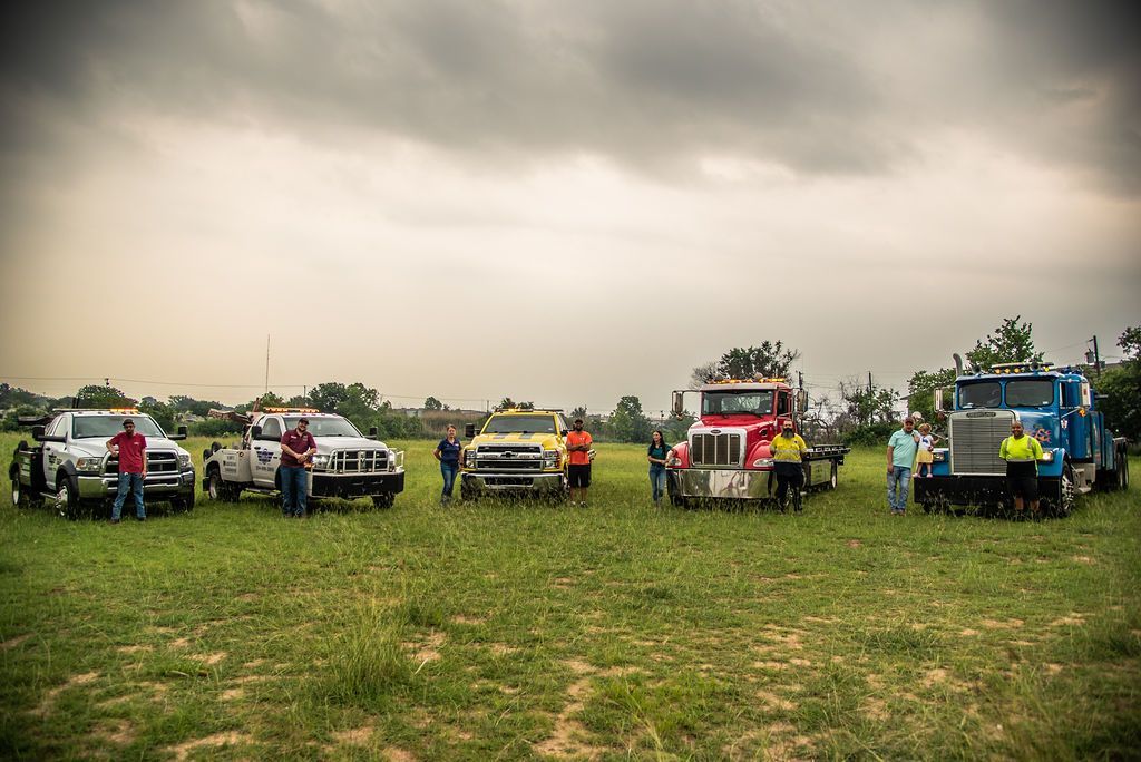 A group of tow trucks are parked in a grassy field. | Chuck's Garage