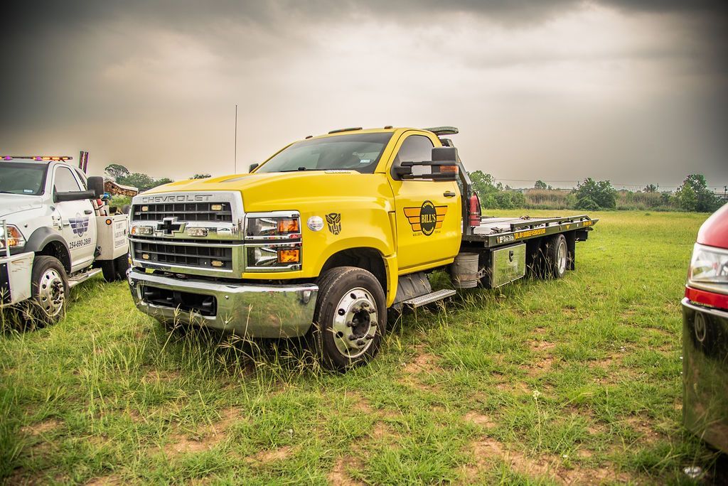 A yellow tow truck is parked in a grassy field. | Chuck's Garage