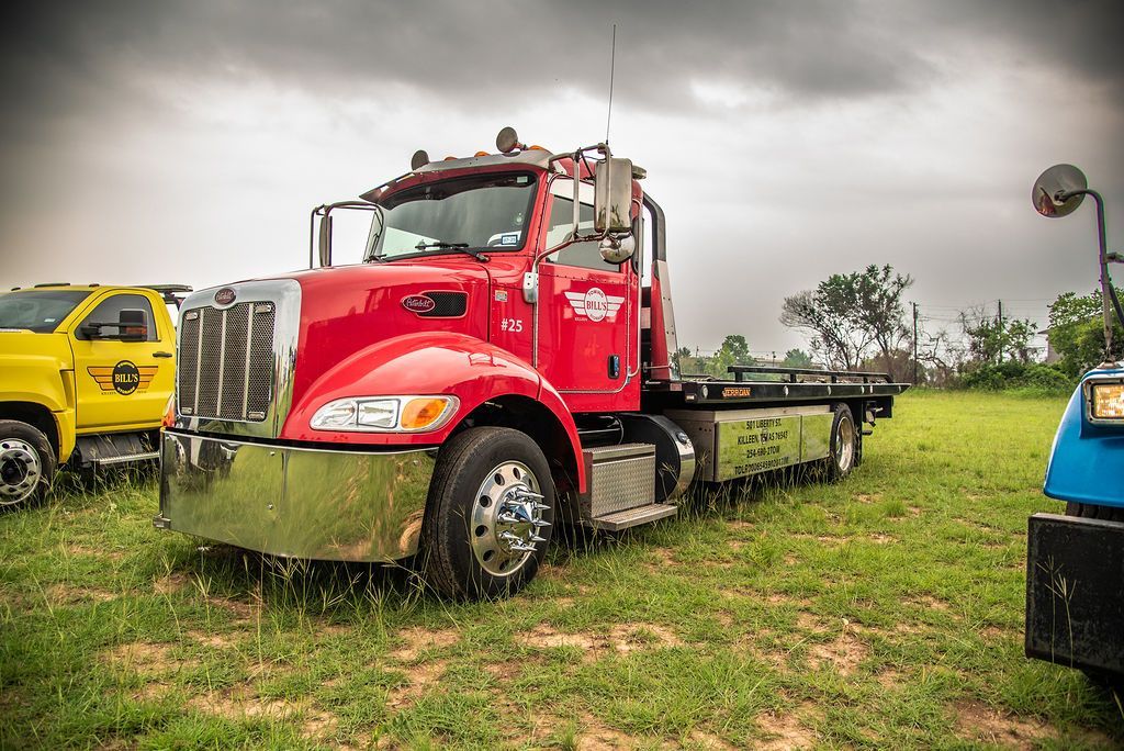 A red tow truck is parked in a grassy field. | Chuck's Garage