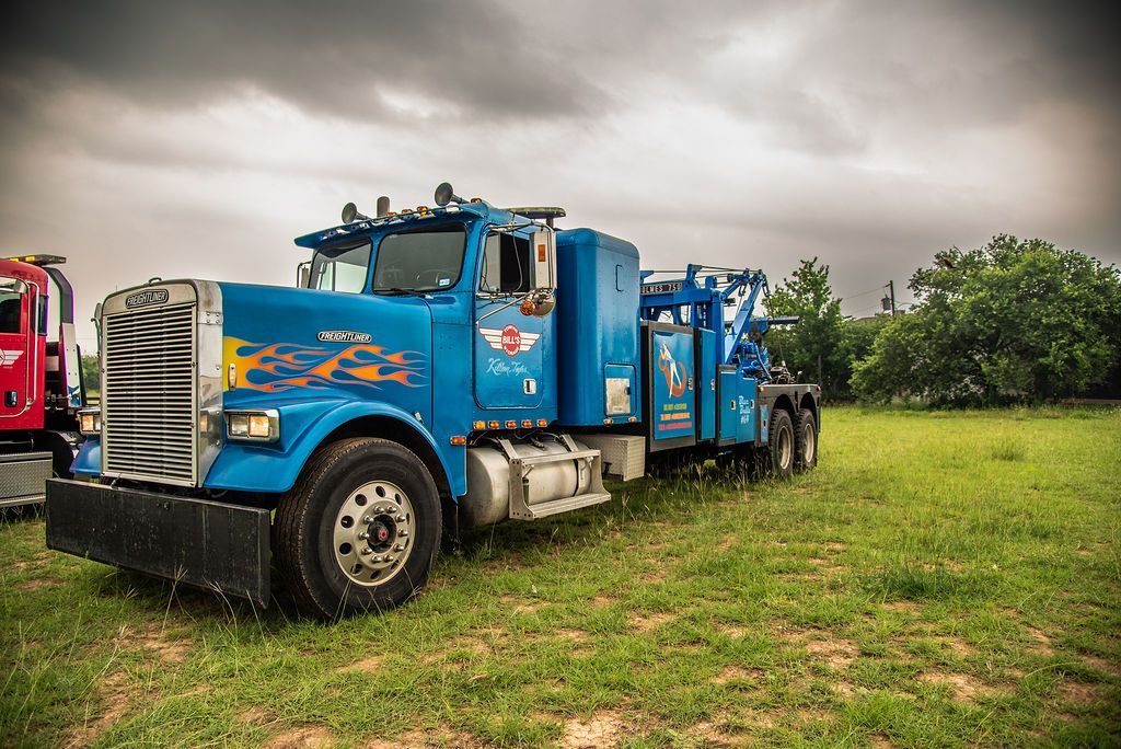 A blue tow truck is parked in a grassy field. | Chuck's Garage
