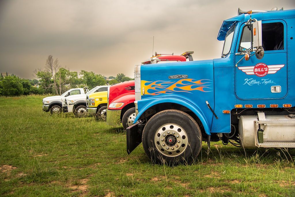 A row of semi trucks are parked in a grassy field. | Chuck's Garage