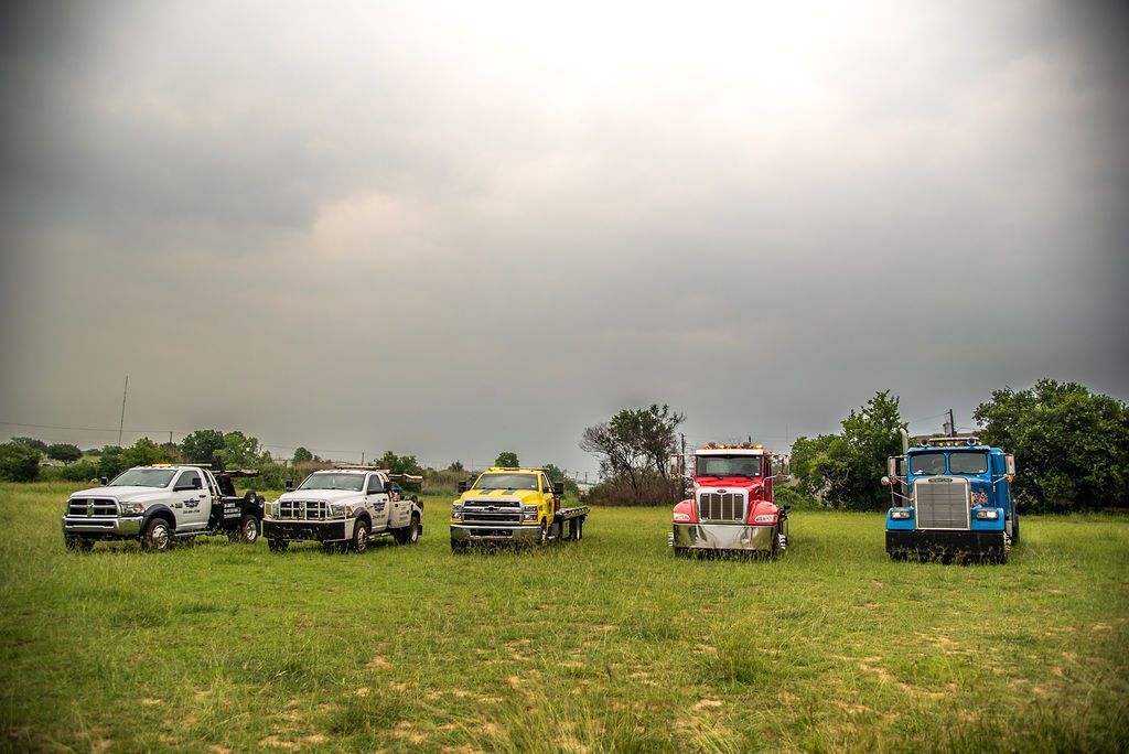 A row of trucks are parked in a grassy field. | Chuck's Garage