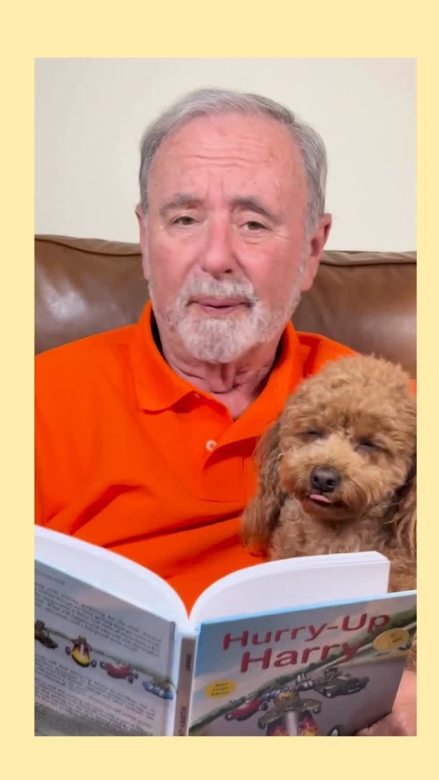 Man in orange shirt reads a book ("Hurry-Up Harry") to a brown poodle, both seated.