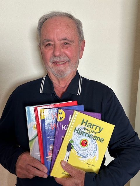 Man smiling, holding colorful children's books.