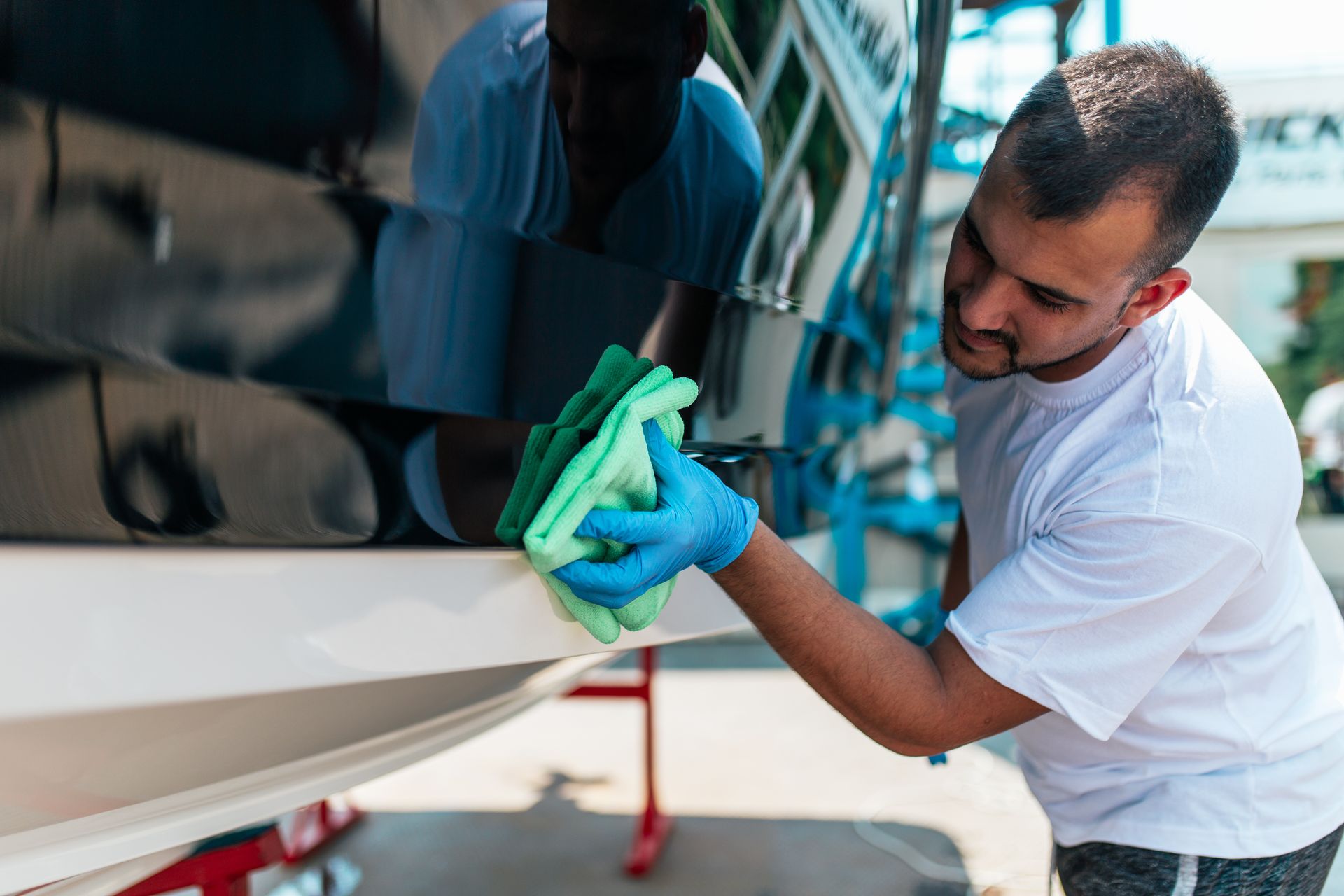 A man is cleaning a boat with a green cloth.