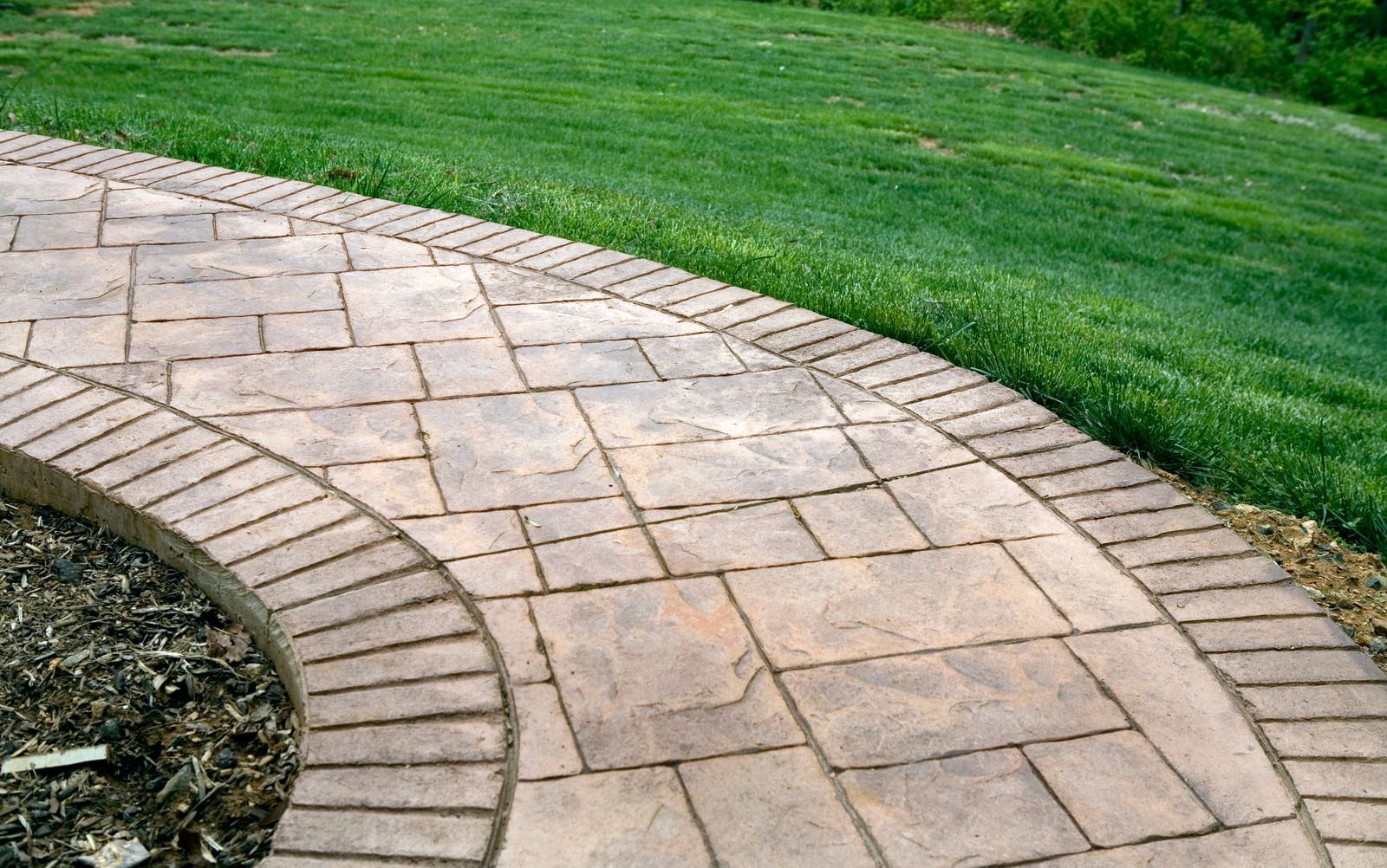 A brick walkway going through a lush green field