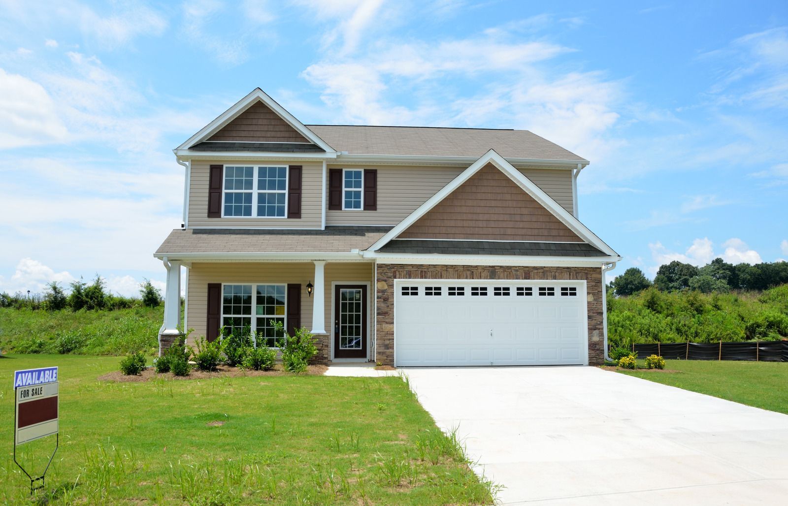 A large house with a for sale sign in front of it.