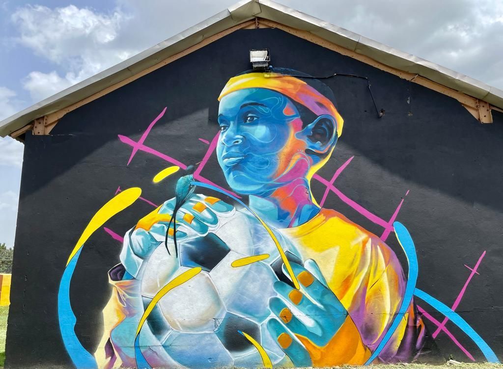 Football player holding a football on a green field at a stadium at night.