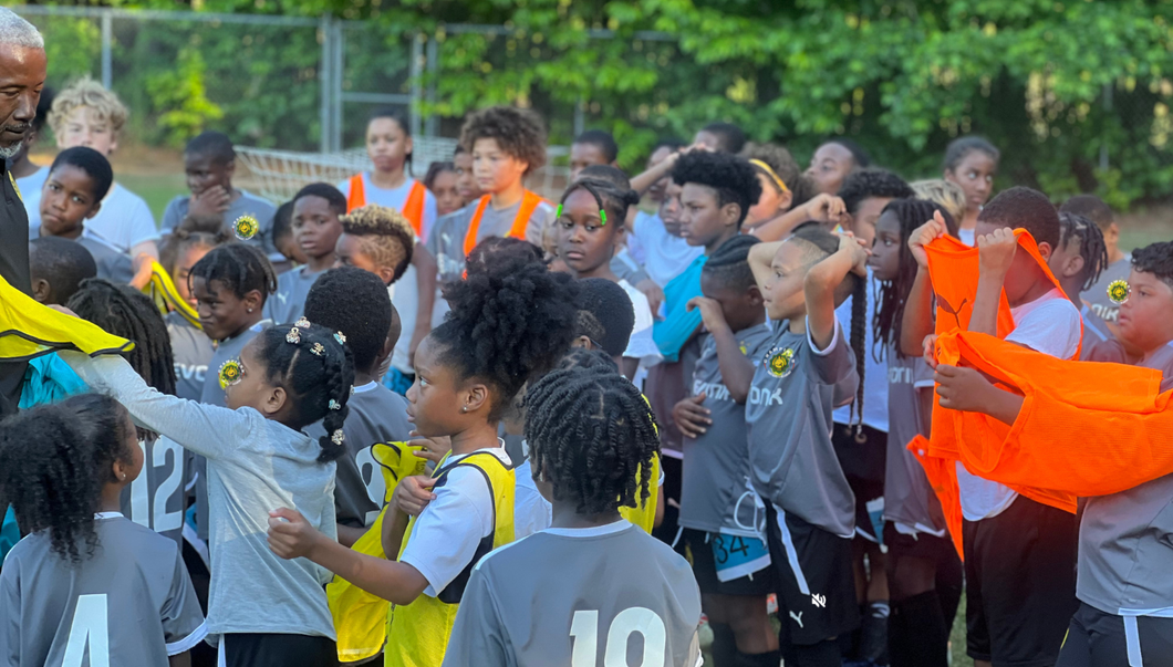 Football player in silver uniform runs with ball on a green field.