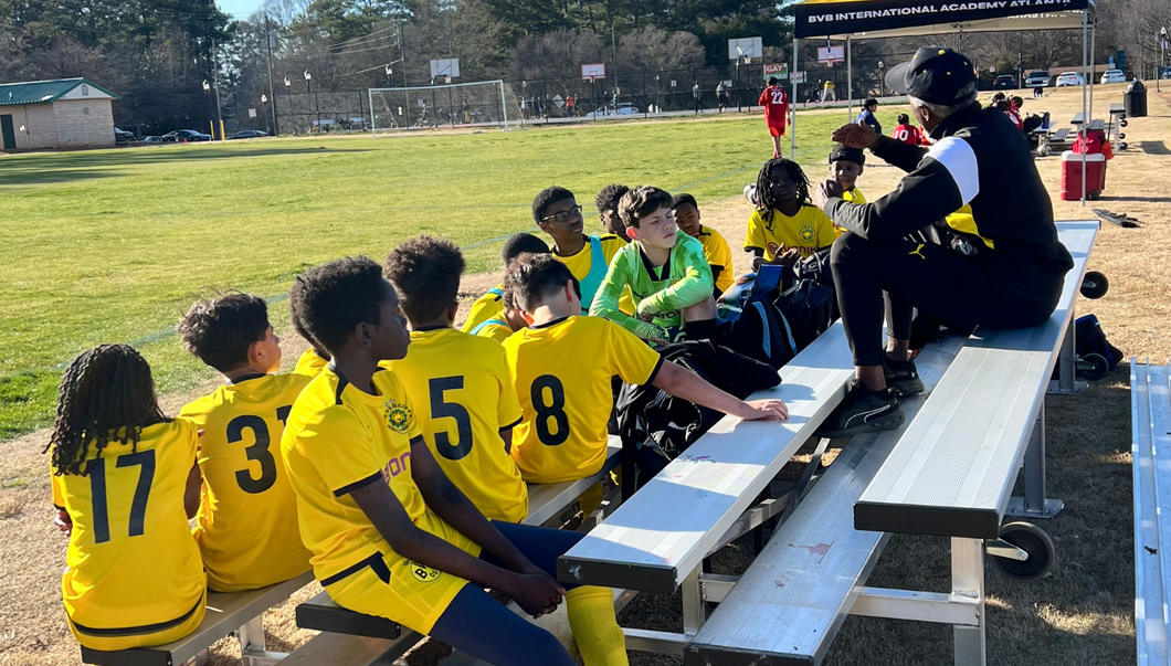 Cheerleader in red uniform performs a backbend on a green and red football field.