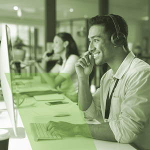 A man wearing headphones is smiling while using a computer