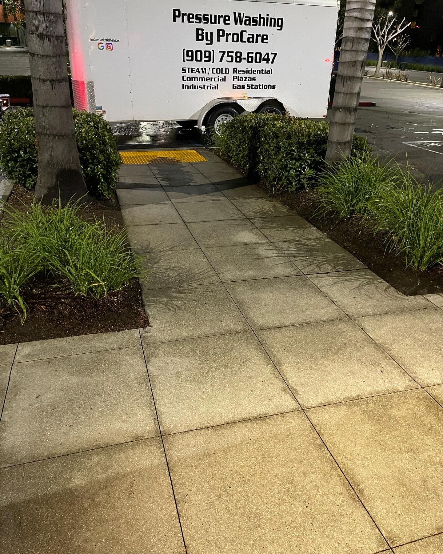 A white trailer is parked on the sidewalk next to a sidewalk.