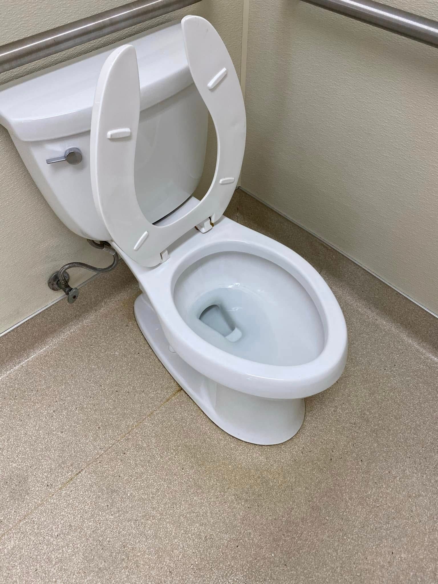 A white toilet with the seat up in a bathroom.