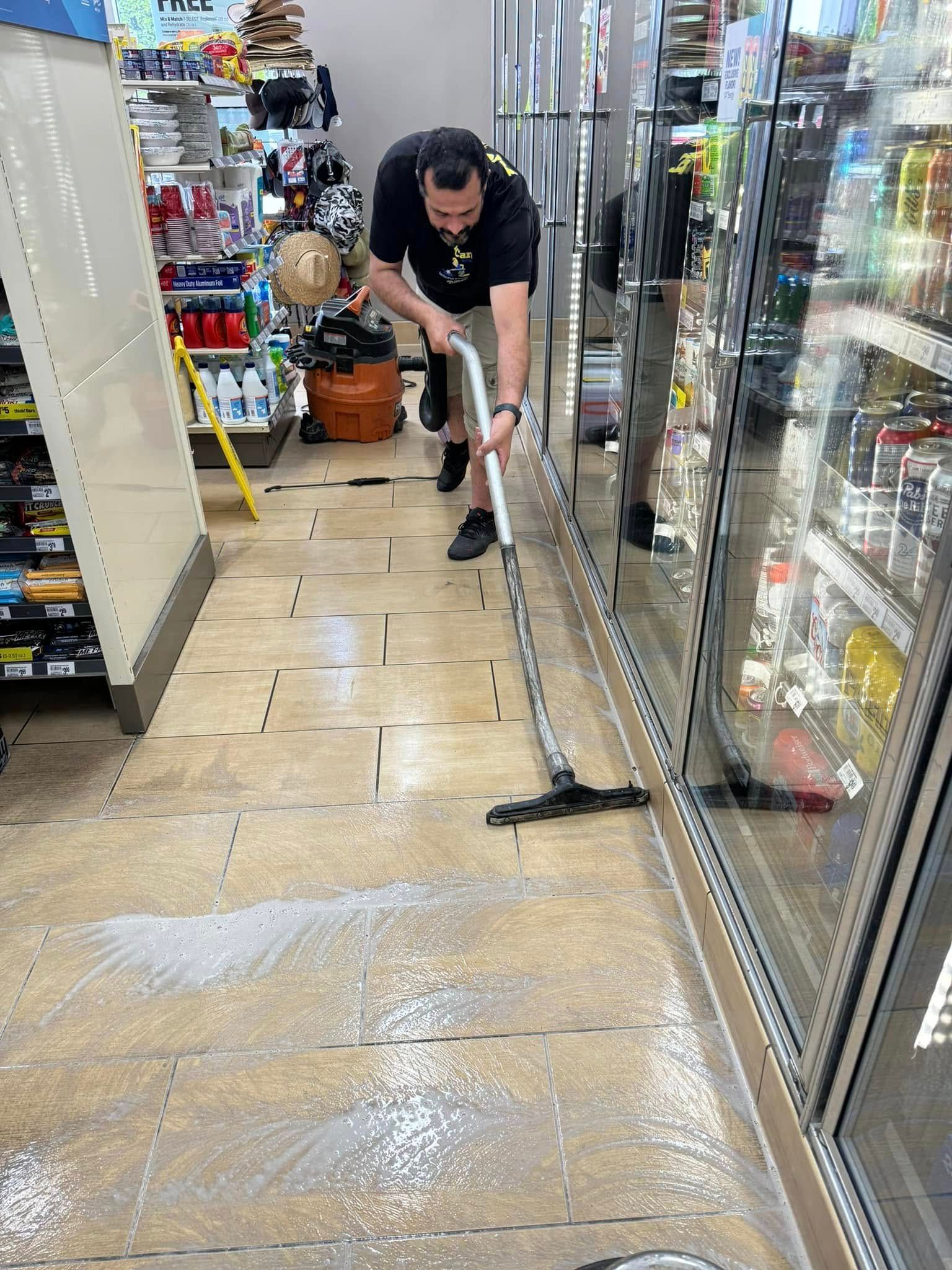 A man is cleaning the floor of a store with a vacuum cleaner.