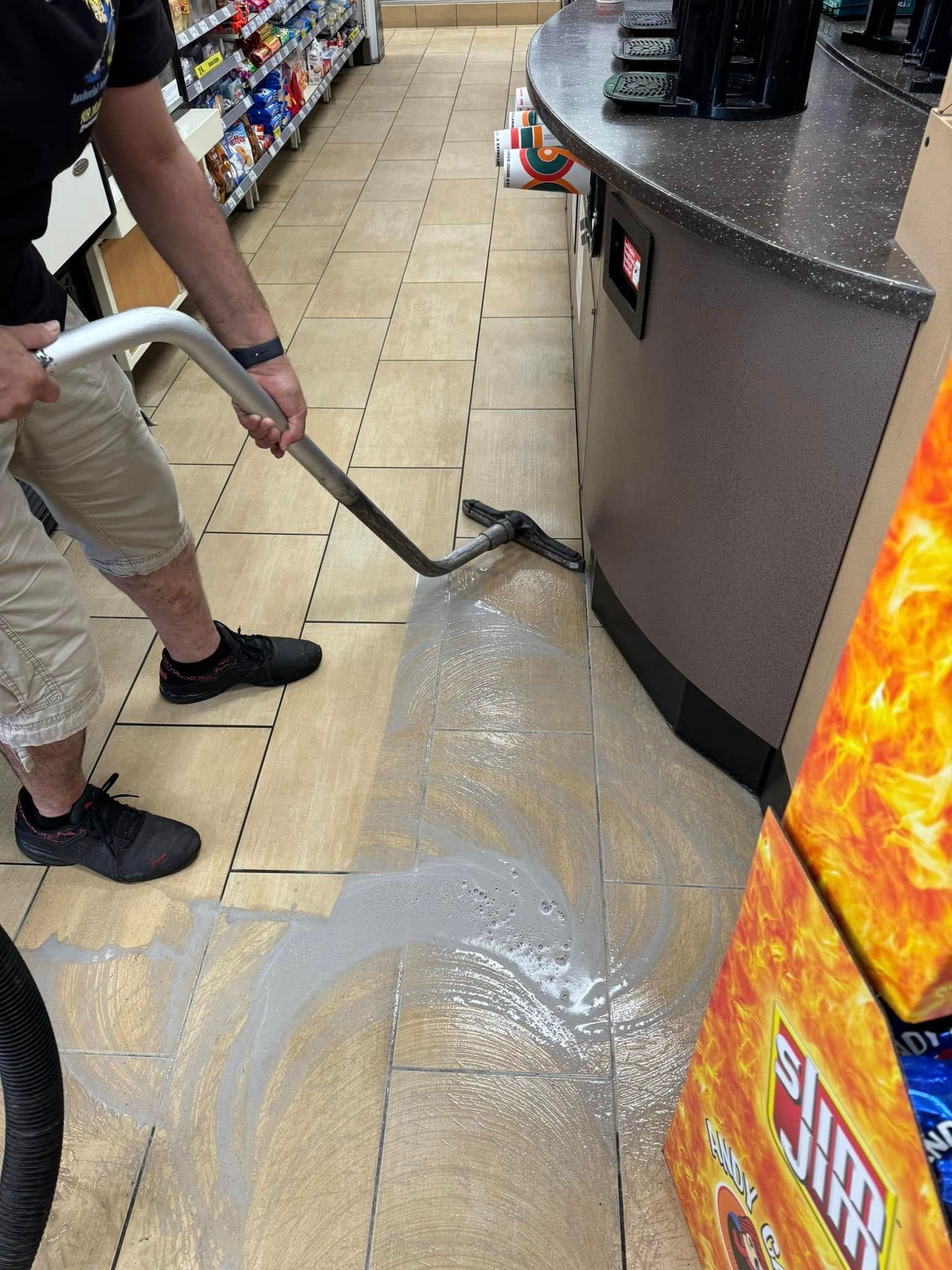 A man is using a vacuum cleaner to clean the floor of a store.