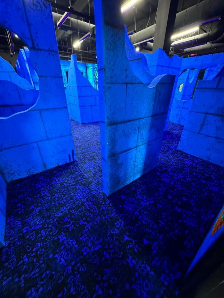 A maze with blue lights on the walls and a purple carpet.