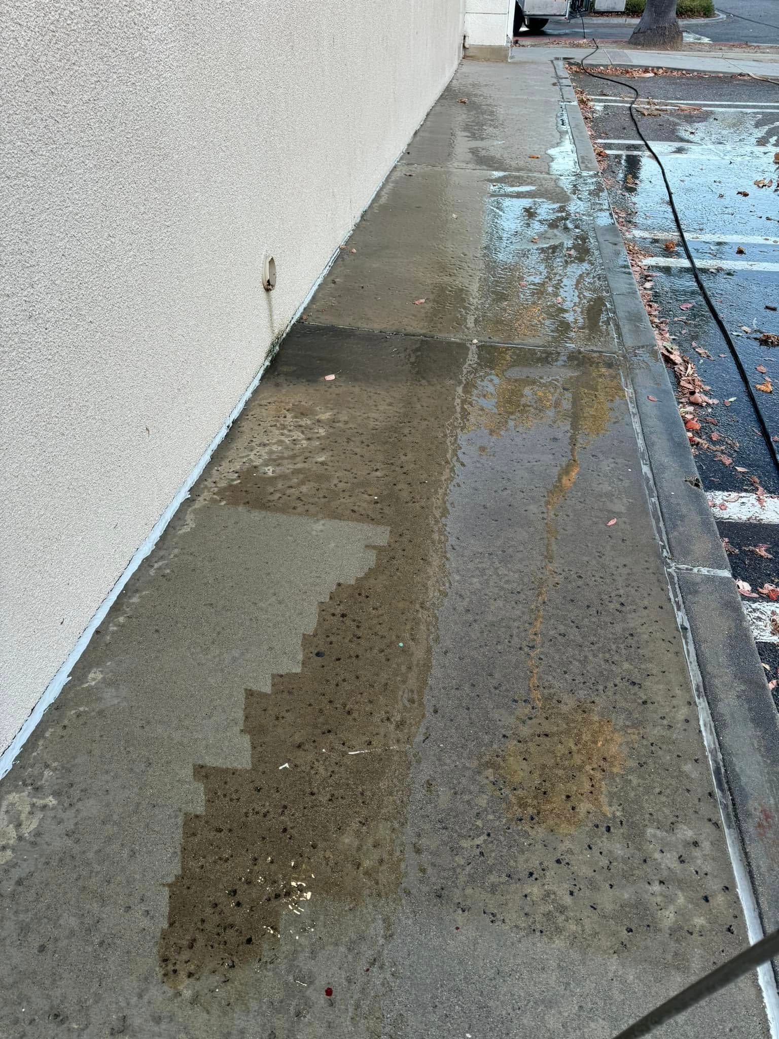 A puddle of water on the sidewalk next to a building.
