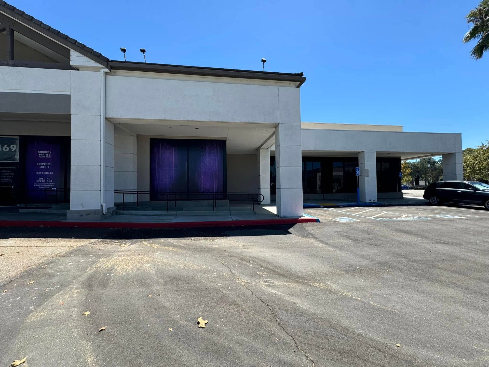 A white building with a purple door and a car parked in front of it.