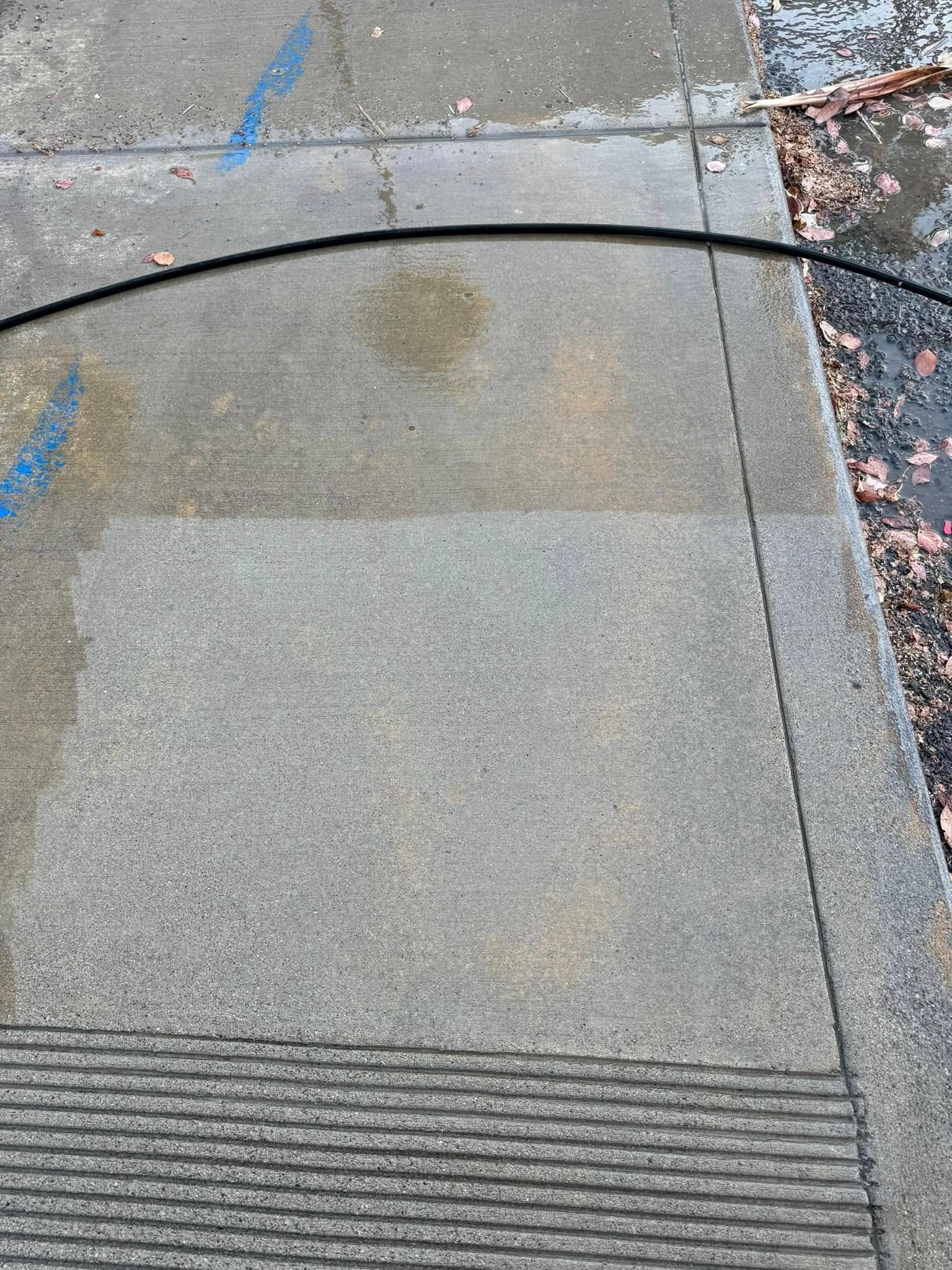 A hose is being used to clean a concrete sidewalk.