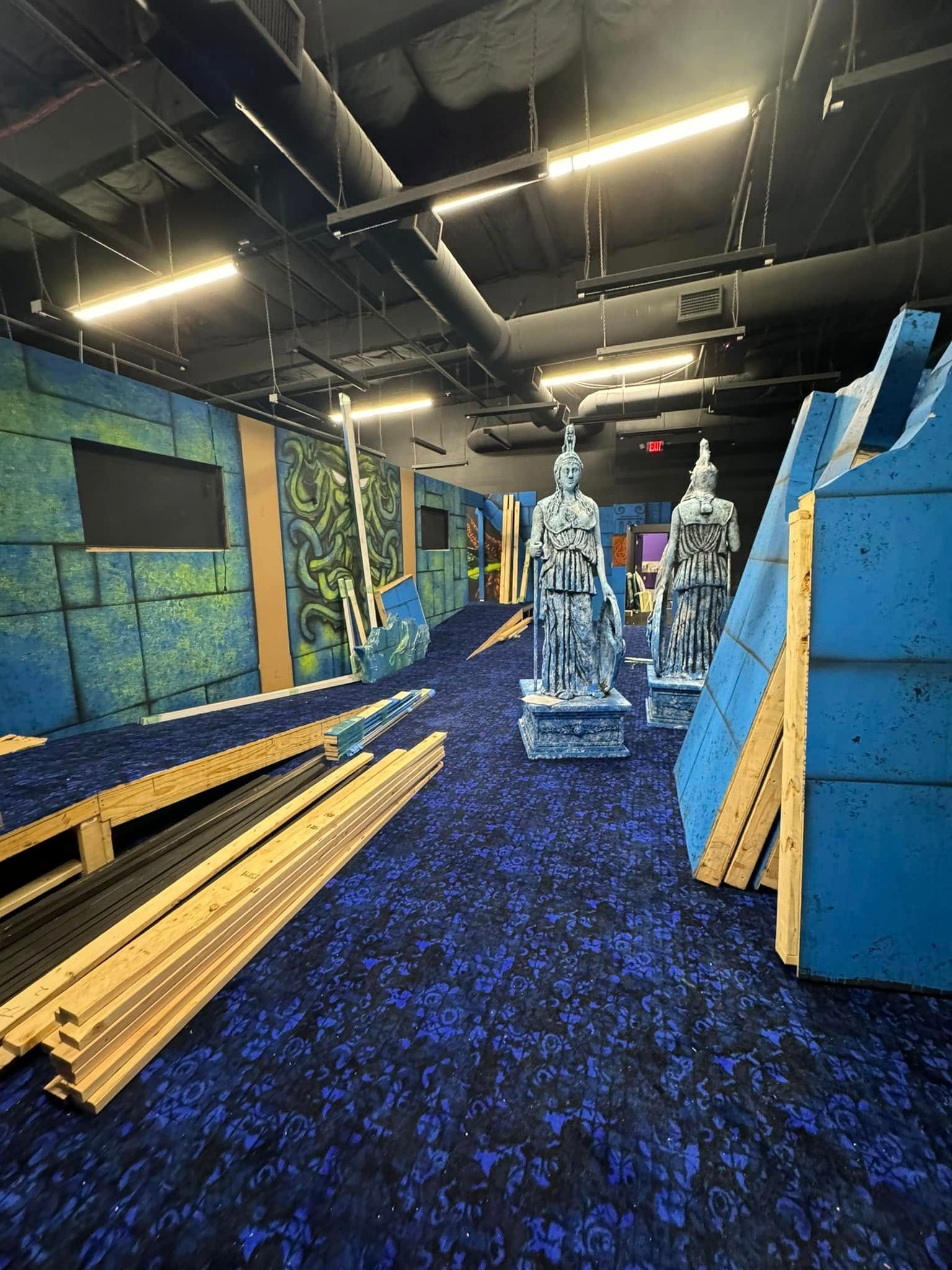 A room with a lot of blue carpet and a bunch of statues on the floor.