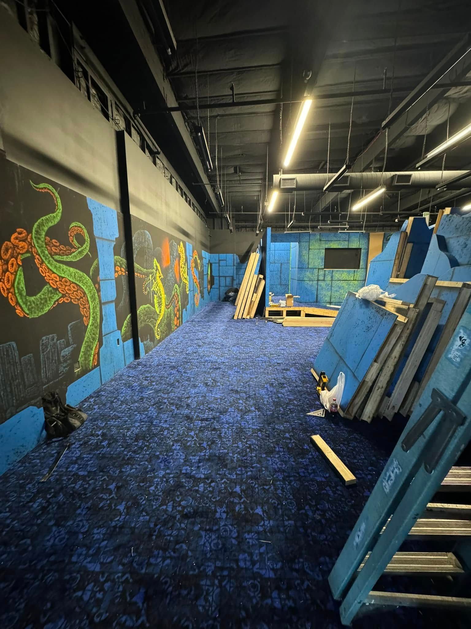 A large room with a blue carpet and a painting on the wall.