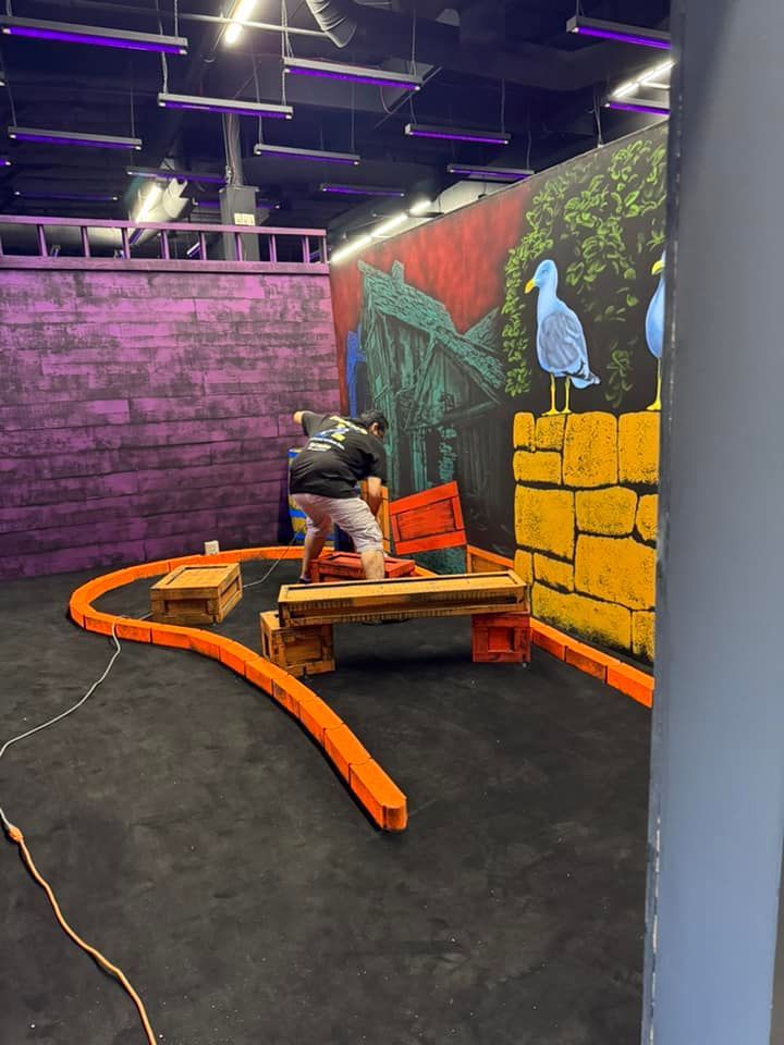 A man is standing in a room with a painting on the wall.