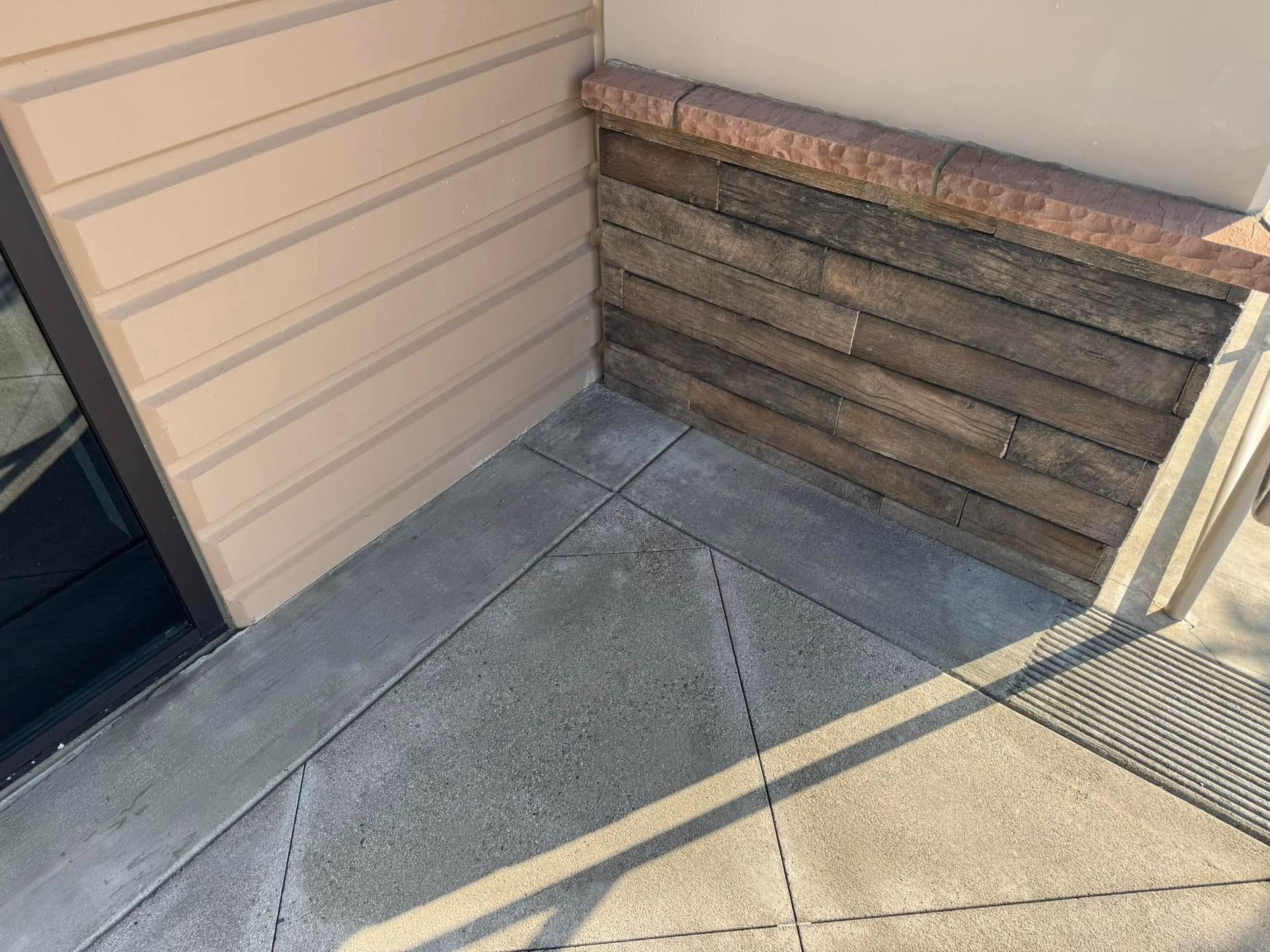 A corner of a building with a brick wall and a concrete floor.