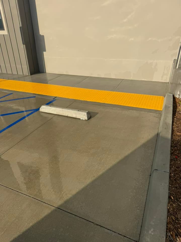 A concrete sidewalk with a yellow curb and a parking block