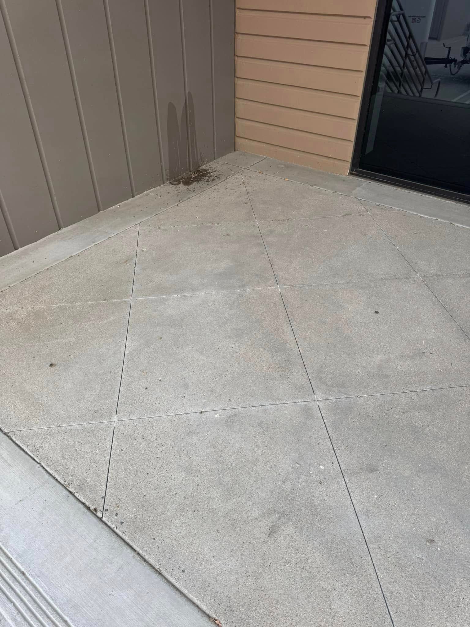 A concrete sidewalk in front of a building with a door.