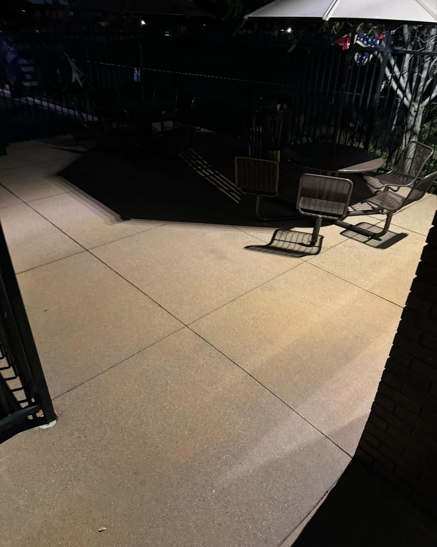 A patio with chairs and umbrellas at night.