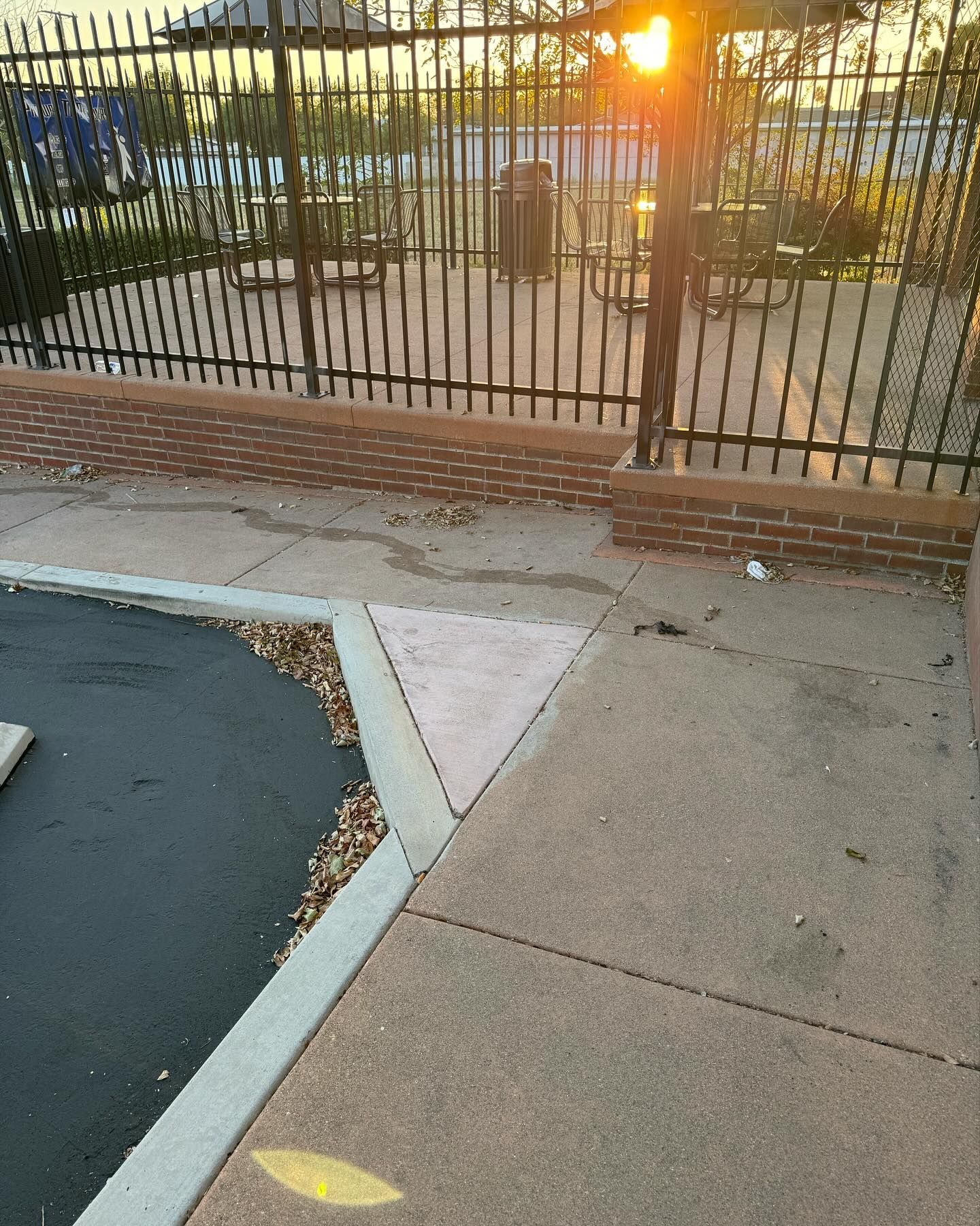 A fence surrounds a parking lot with a brick wall
