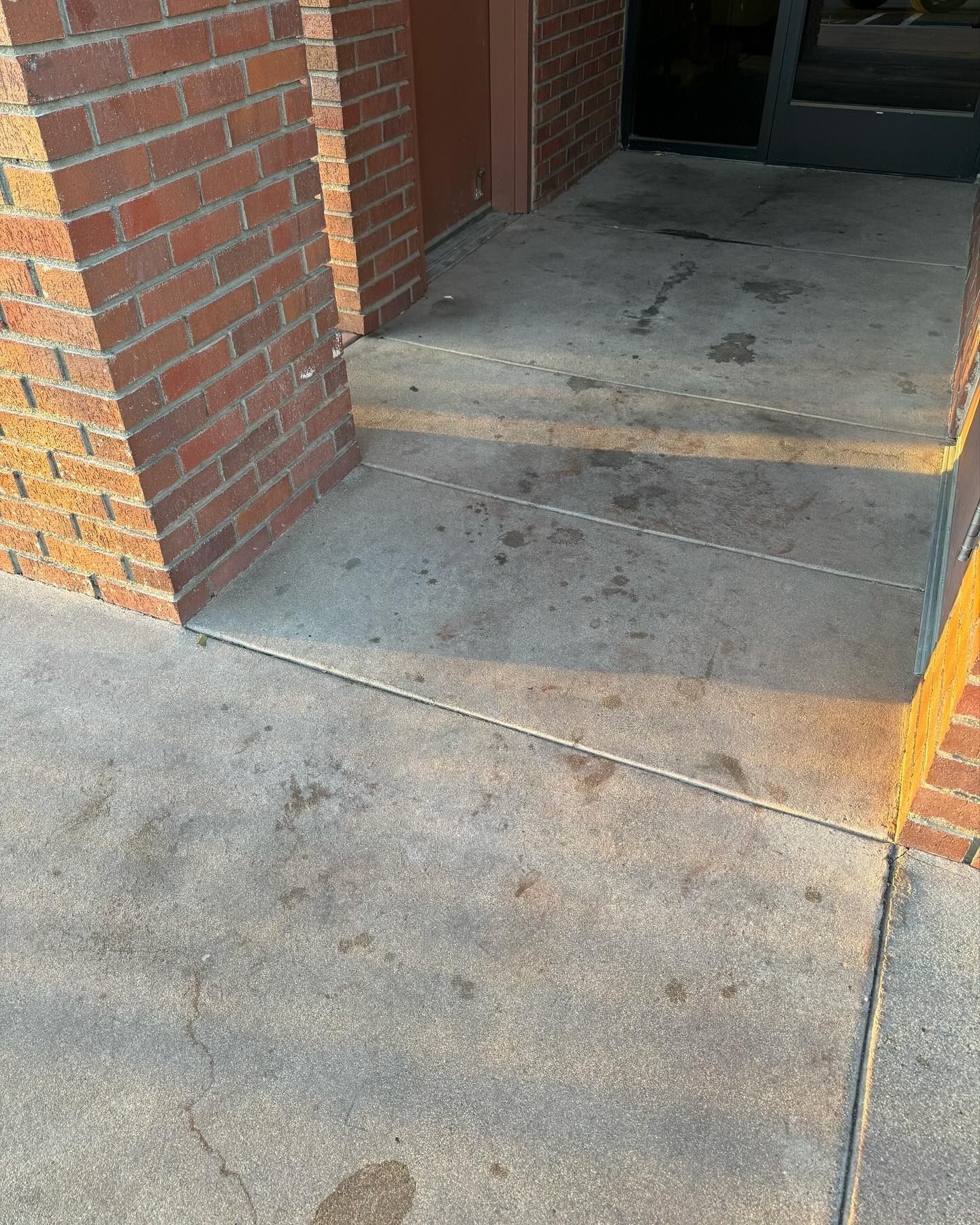 A brick building with a concrete sidewalk in front of it.