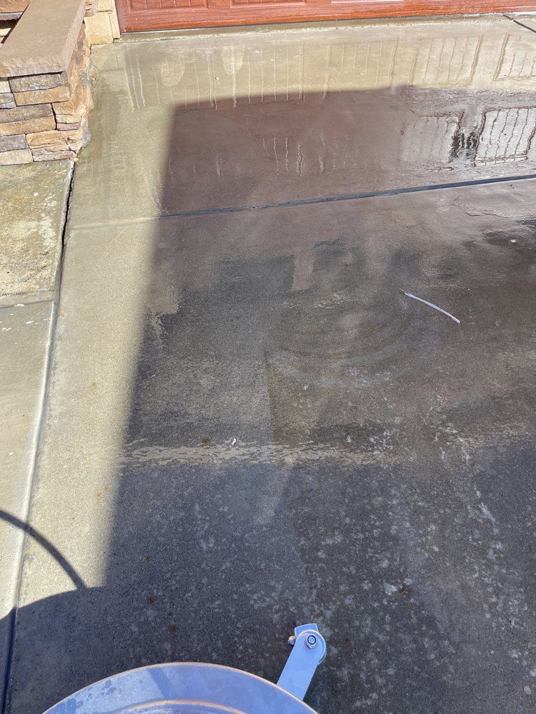 A concrete driveway is being cleaned with a pressure washer.