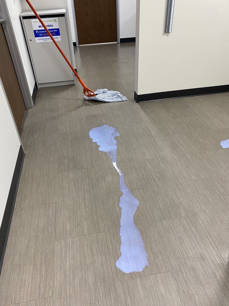 A mop is being used to clean a spilled liquid on the floor.