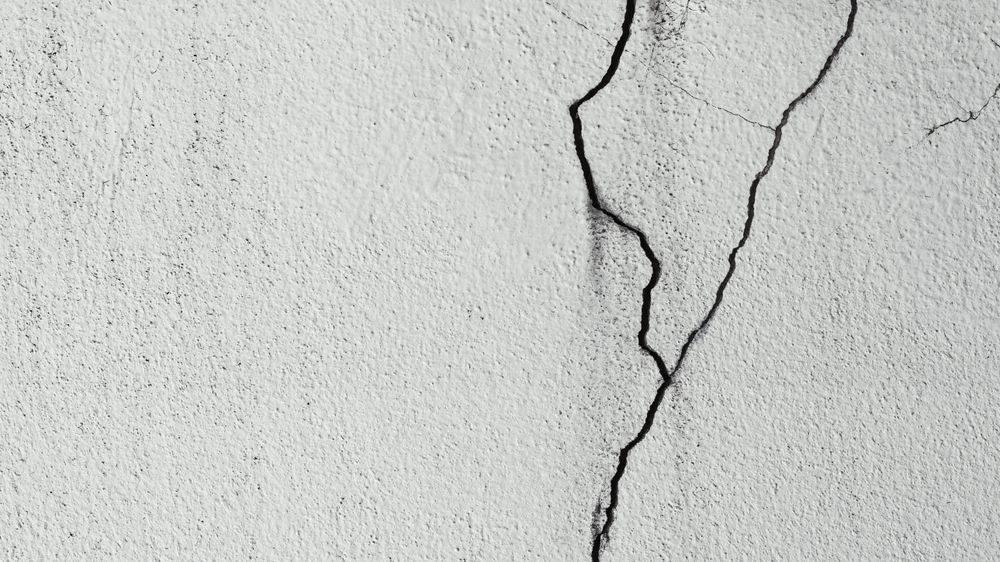 Modern living room with beige sofa, artwork, dining area, and dark wood floors.