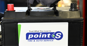 A Point S Tire & Auto Service branded car battery with a red positive terminal and a black negative terminal.
