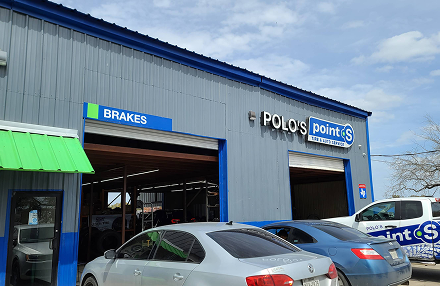 The exterior of Polo’s Point S automotive repair shop, featuring blue and gray siding with cars parked in front.