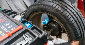 A close-up of a tire being balanced on a diagnostic machine in an automotive shop.