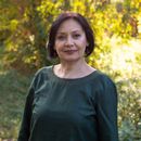 Woman in a dark green sweater standing outdoors in soft natural light