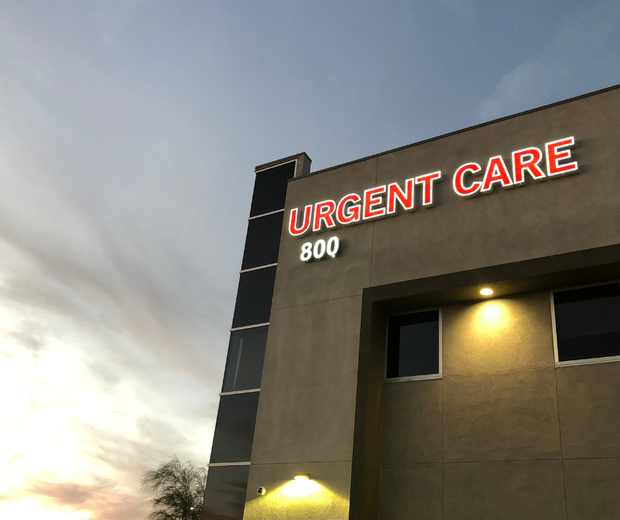 Urgent care building at dusk with red neon sign and illuminated exterior lights