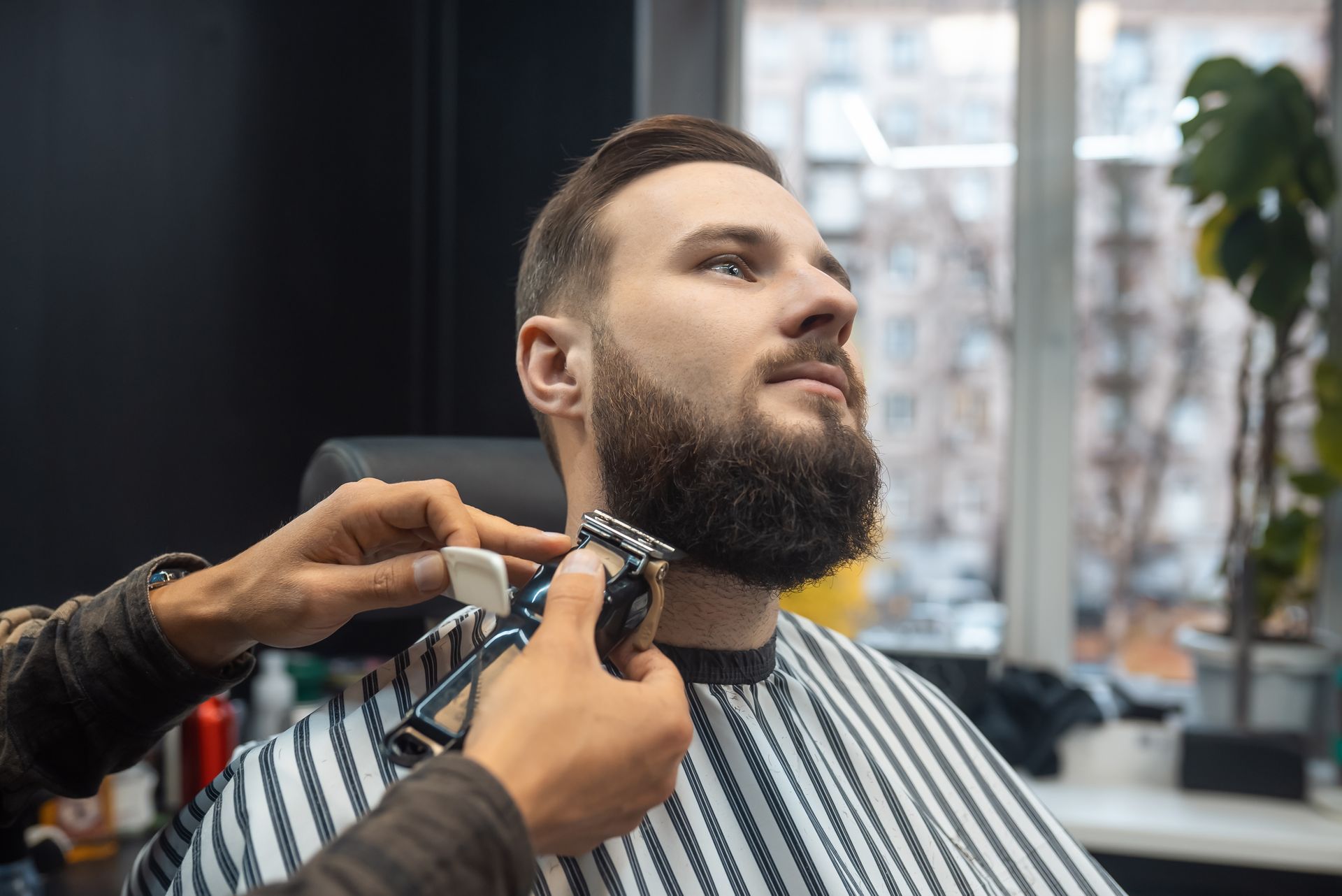 A man is getting his beard cut by a barber in a barber shop.