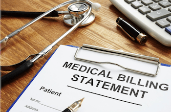 Medical billing statement on a clipboard with stethoscope, pen, and calculator on a wooden desk.