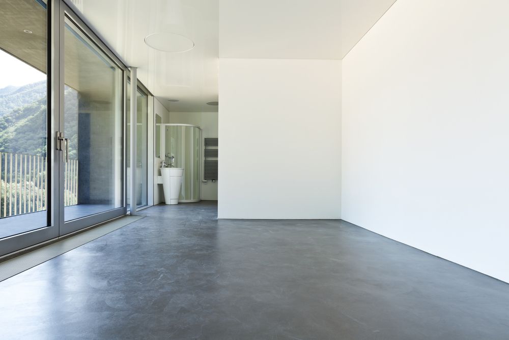 An Empty Room With a Concrete Floor and Sliding Glass Doors — Brett Rayner Cement Rendering In Lennox Head, NSW
