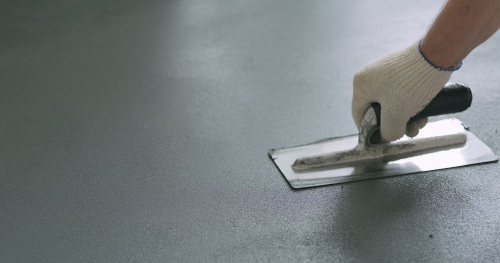 A Person is Using a Trowel on a Concrete Floor — Brett Rayner Cement Rendering In Murwillumbah, NSW